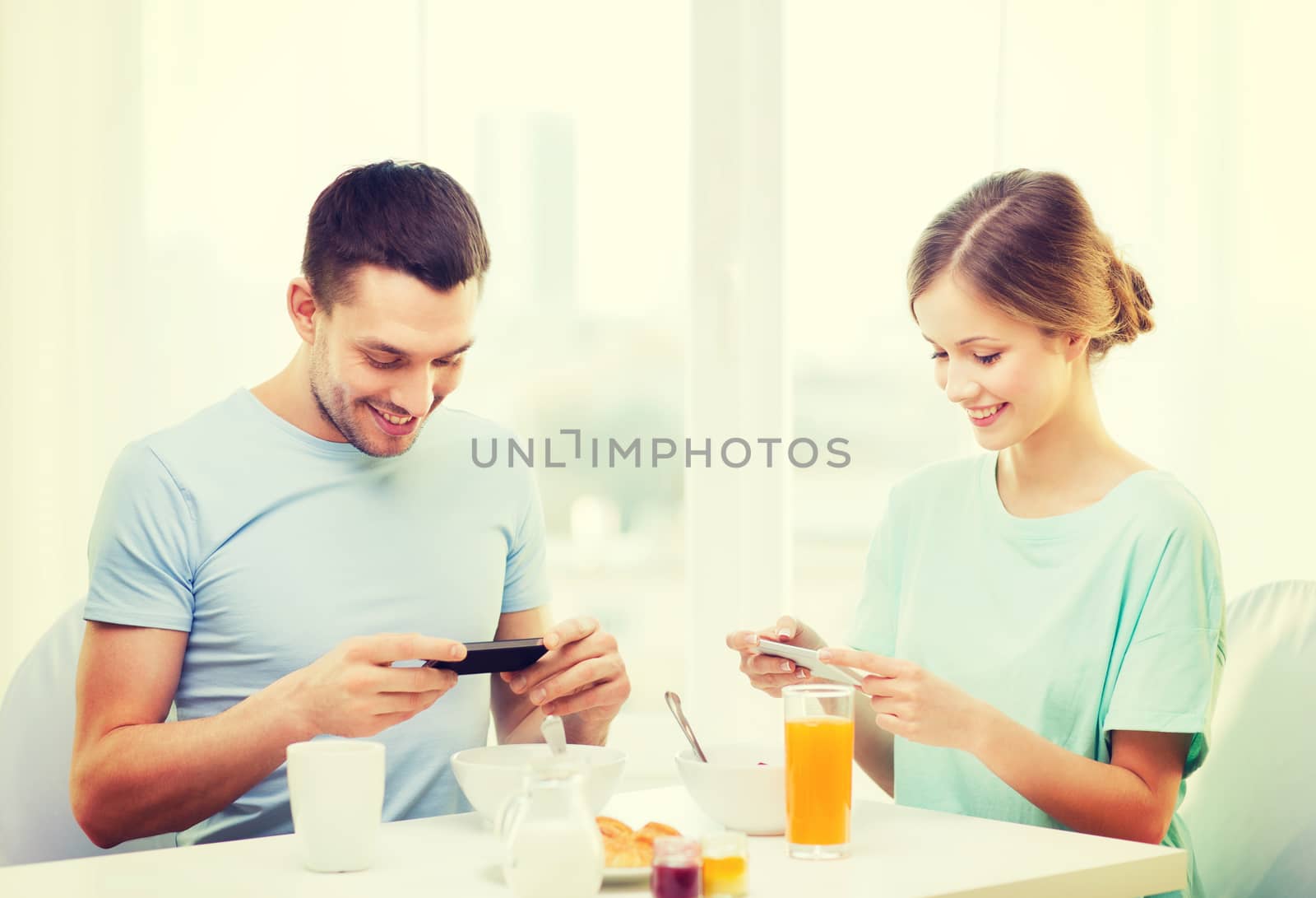 food, home, couple and technology concept - smiling couple with smartphones teaking picture of breakfast at home