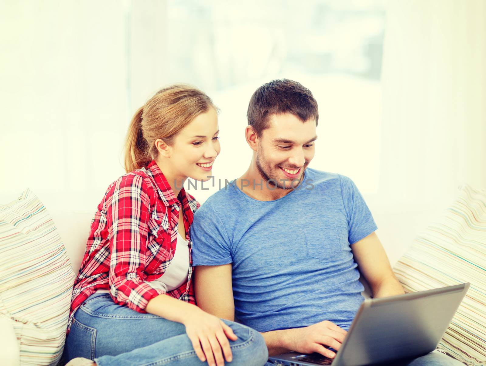 smiling couple with laptop computer at home by dolgachov