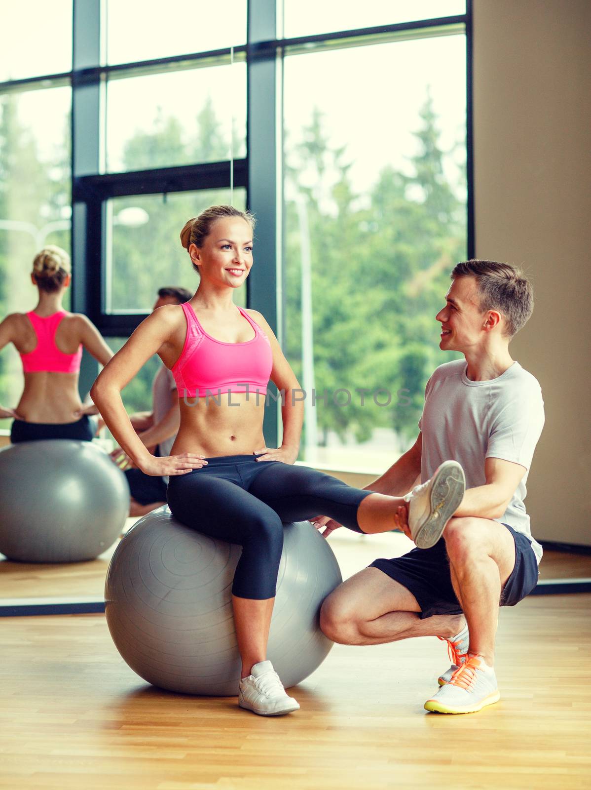 smiling man and woman with exercise ball in gym by dolgachov