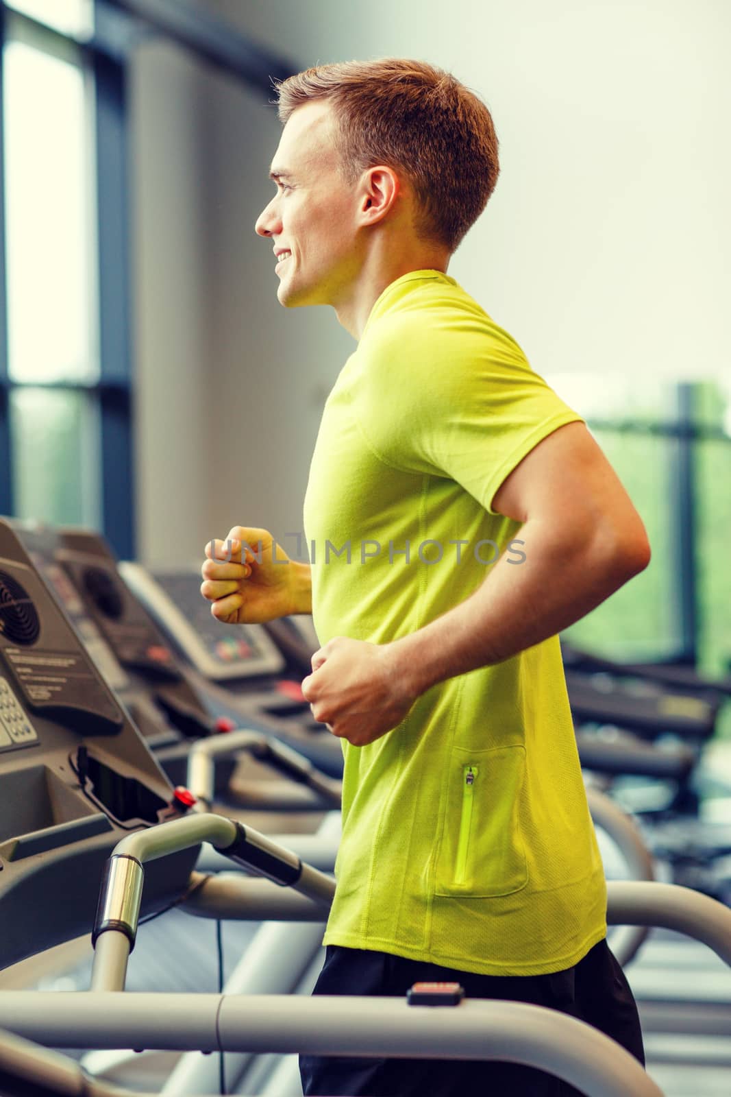 sport, fitness, lifestyle, technology and people concept - smiling man exercising on treadmill in gym