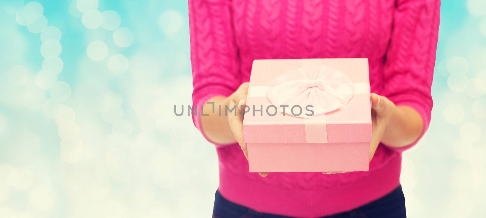 close up of woman in pink sweater holding gift box by dolgachov