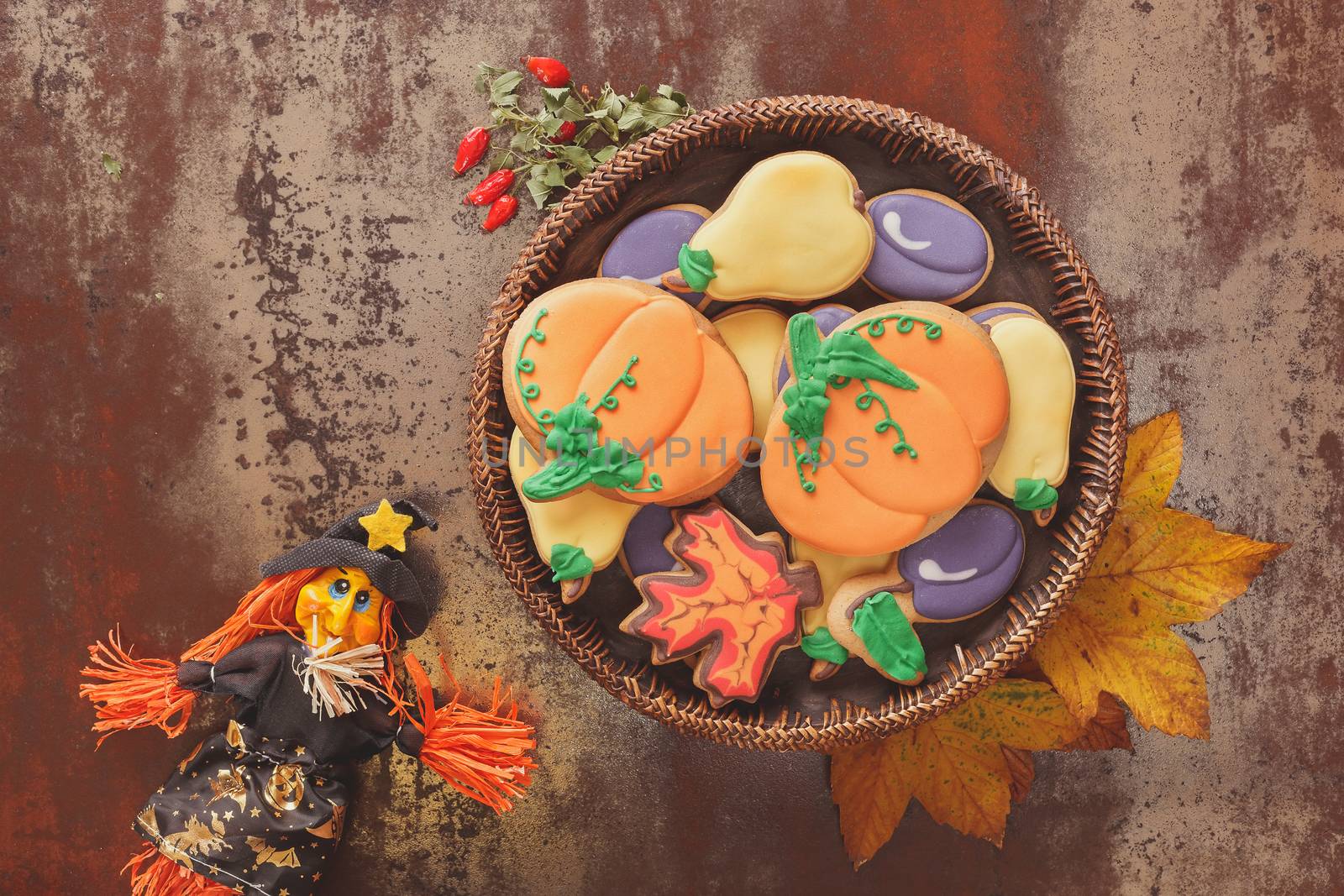 Decorated cookies and witch on rustic table