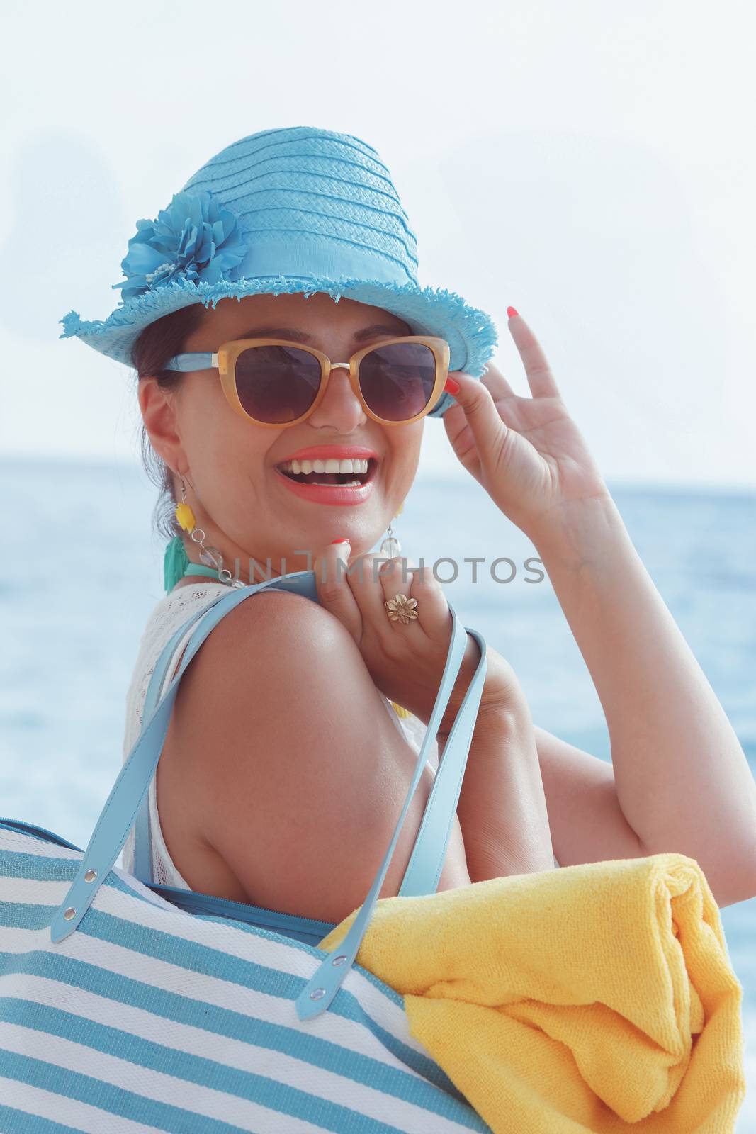 Beautiful woman smiling and carrying bag on the beach