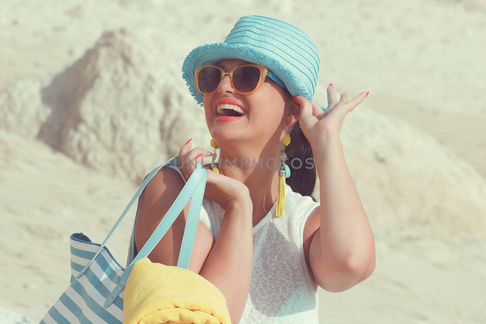 Beautiful woman smiling and carrying bag on the sandy beach. Summer vacation concept. Vintage style, selective focus