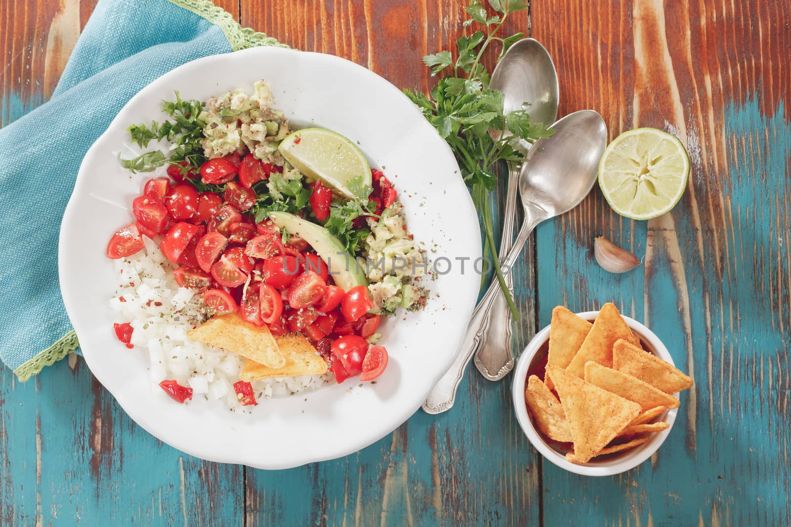 Pico de gallo and nacho chips on rustic wooden table background. Natural light