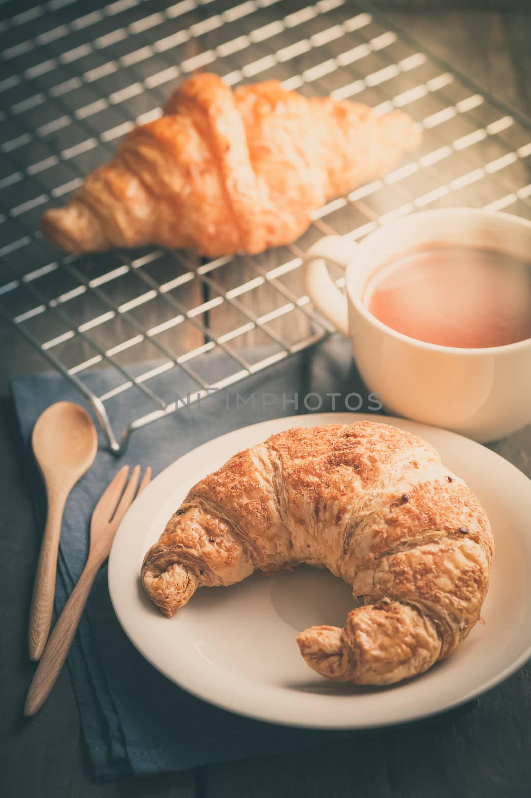 Butter croissant and whole wheat croissant with a cup of hot chocolate on wood table in morning time with film filter effect
