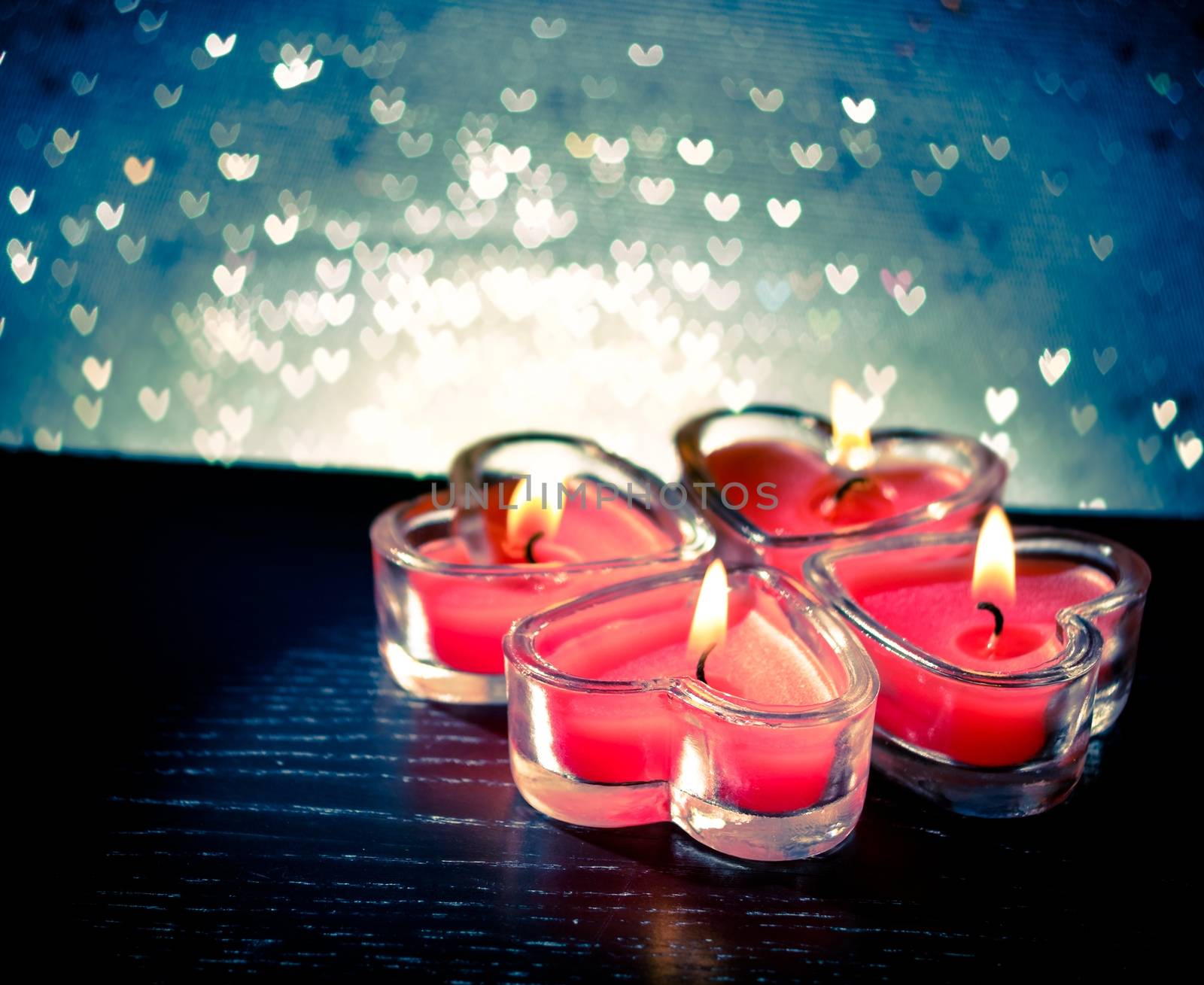 red burning heart shaped candles on blue hearts bokeh by donfiore