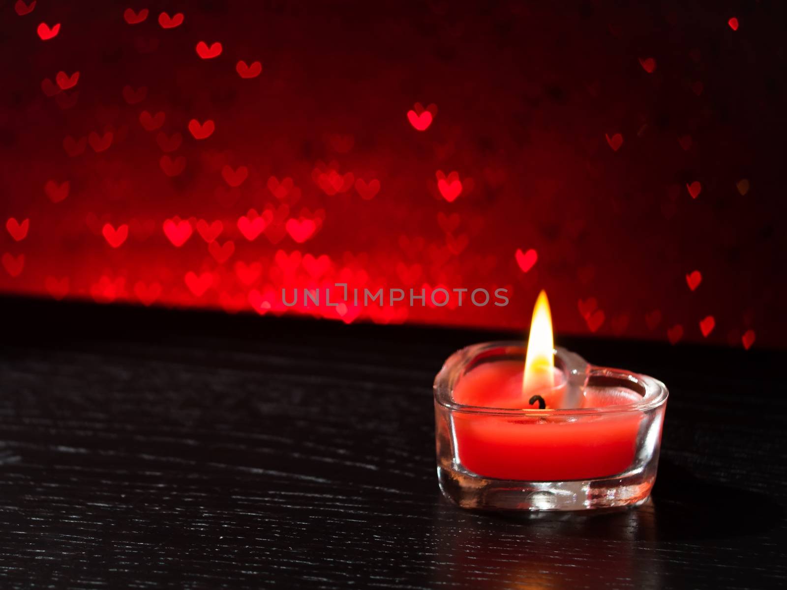 red burning heart shaped candle on red hearts bokeh background, valentine day and love concept