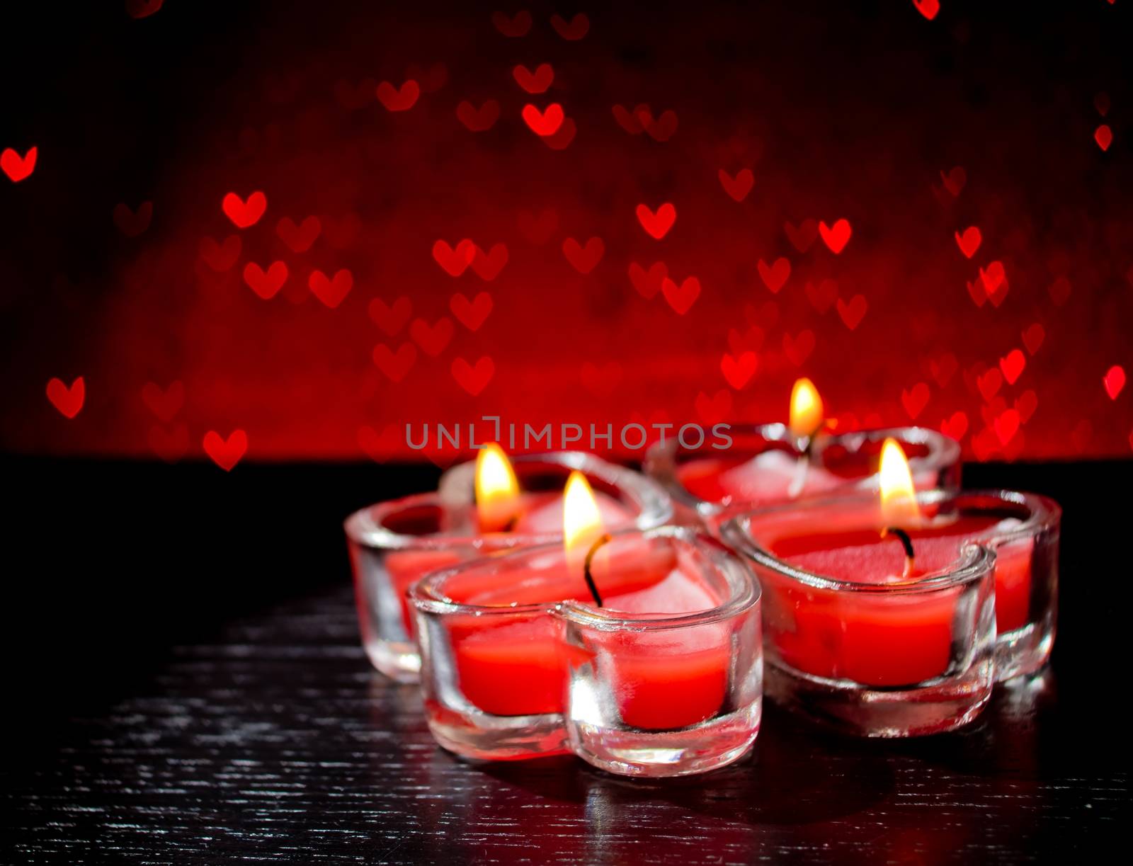 red burning heart shaped candles on red hearts bokeh by donfiore