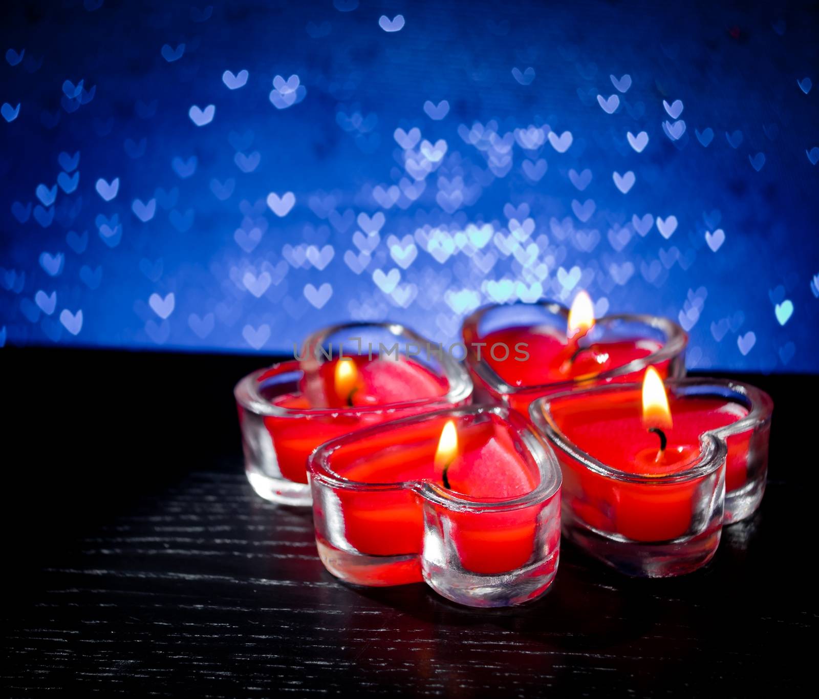 red burning heart shaped candles on blue hearts bokeh by donfiore