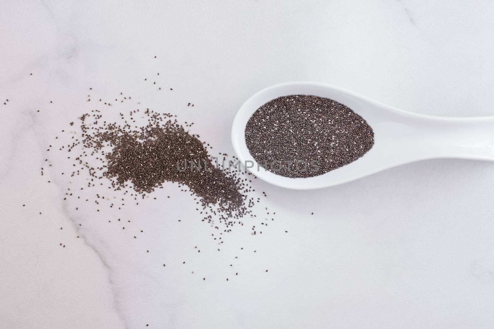Raw whole chia seeds in ceramic spoon. Natural light