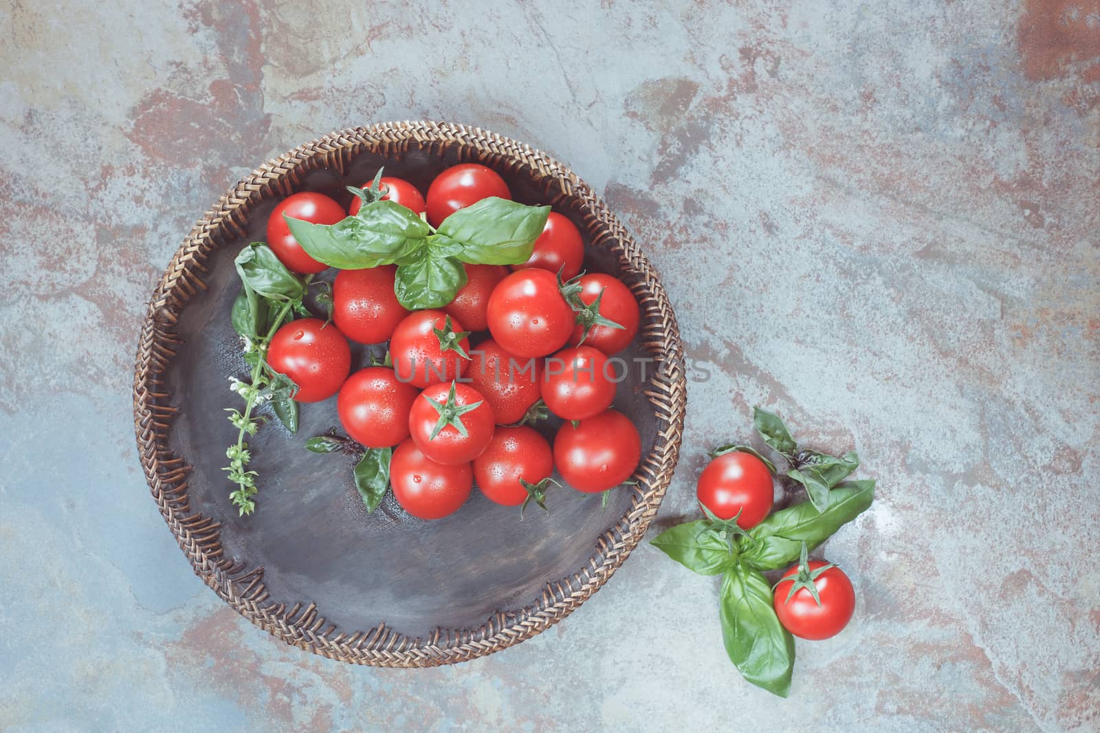 Tomatoes in a wooden bowl on rustic table. Overhead view with retro style processing. Natural light