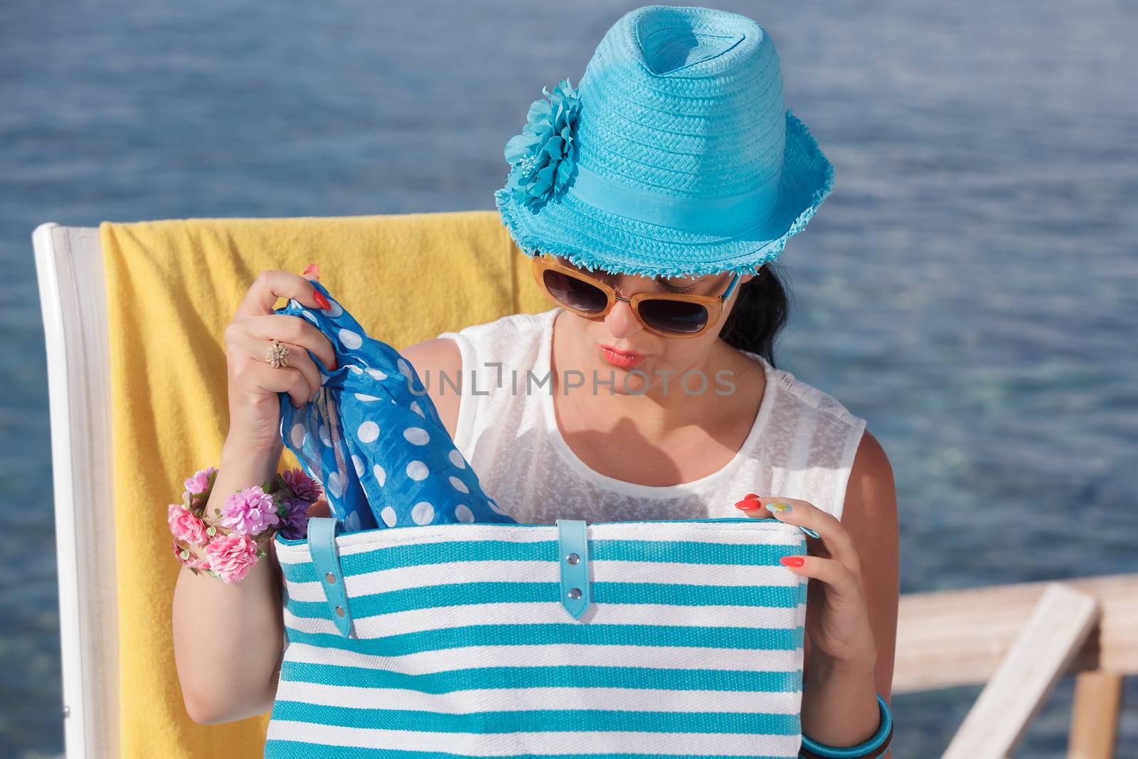 Beautiful woman looking into her bag on the beach . Vintage style, selective focus