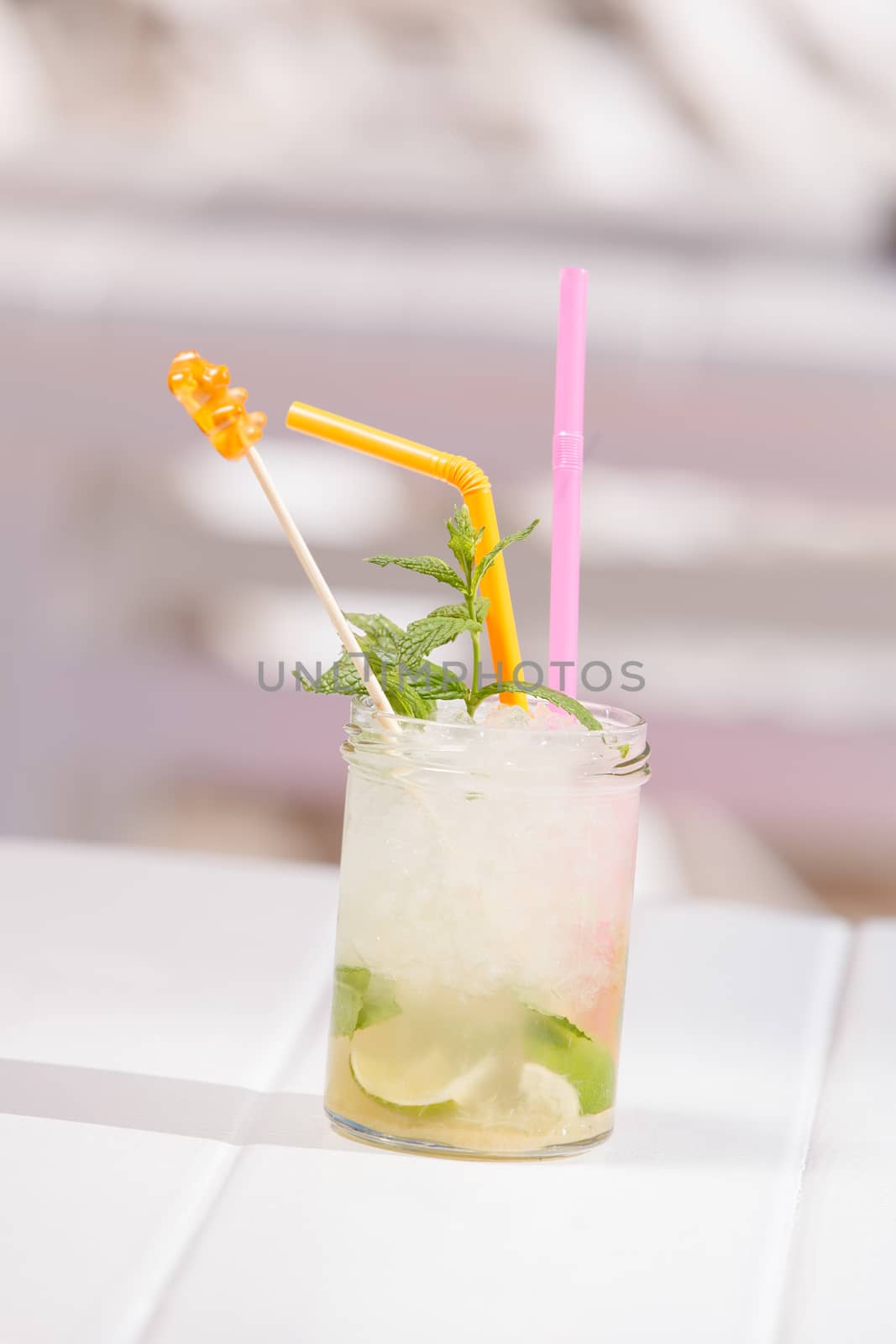 A jar of mojito cocktail with ice and a straw at a beach bar. Selective focus