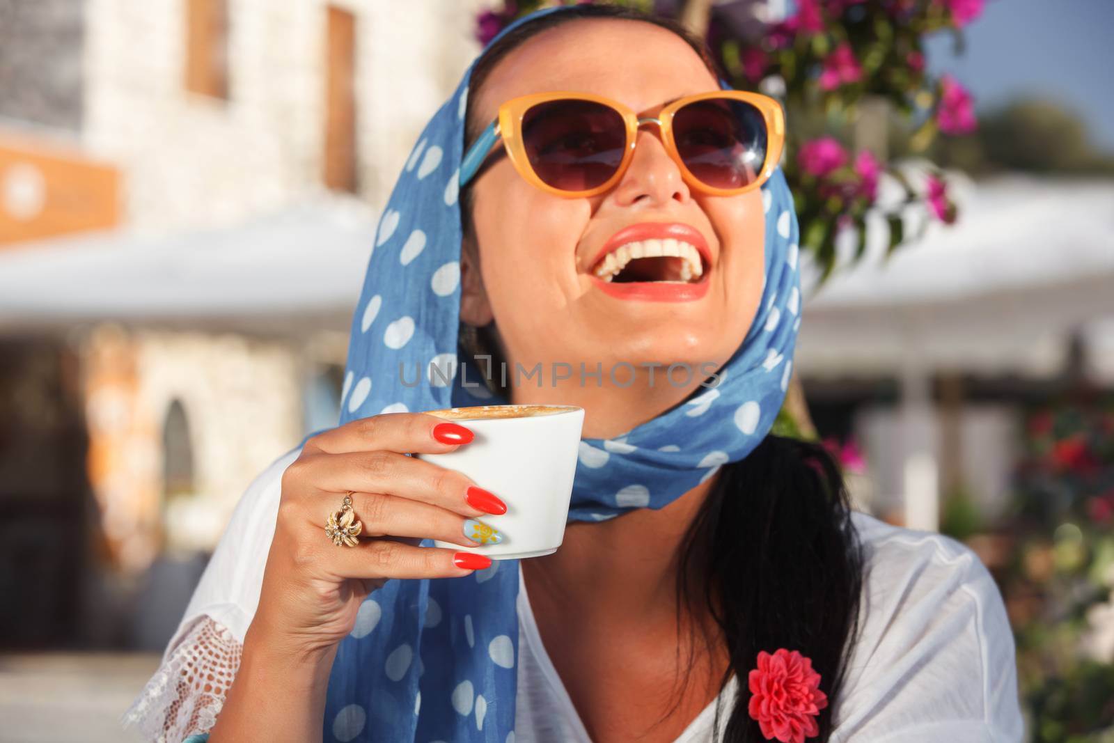 Happy woman drinking coffee In a cafe outdoors, in the sunset. Vintage style, focus on cup of coffee. Shallow depth of field.