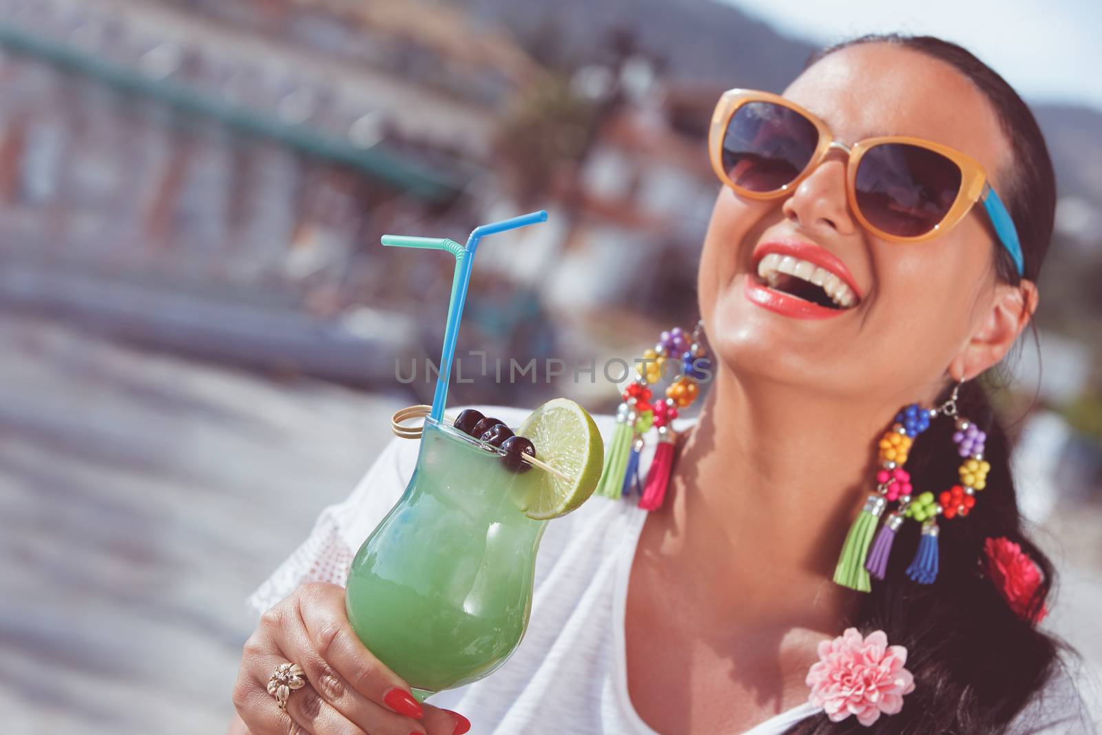 Happy young woman holding a glass of cocktail near the yacht marine.