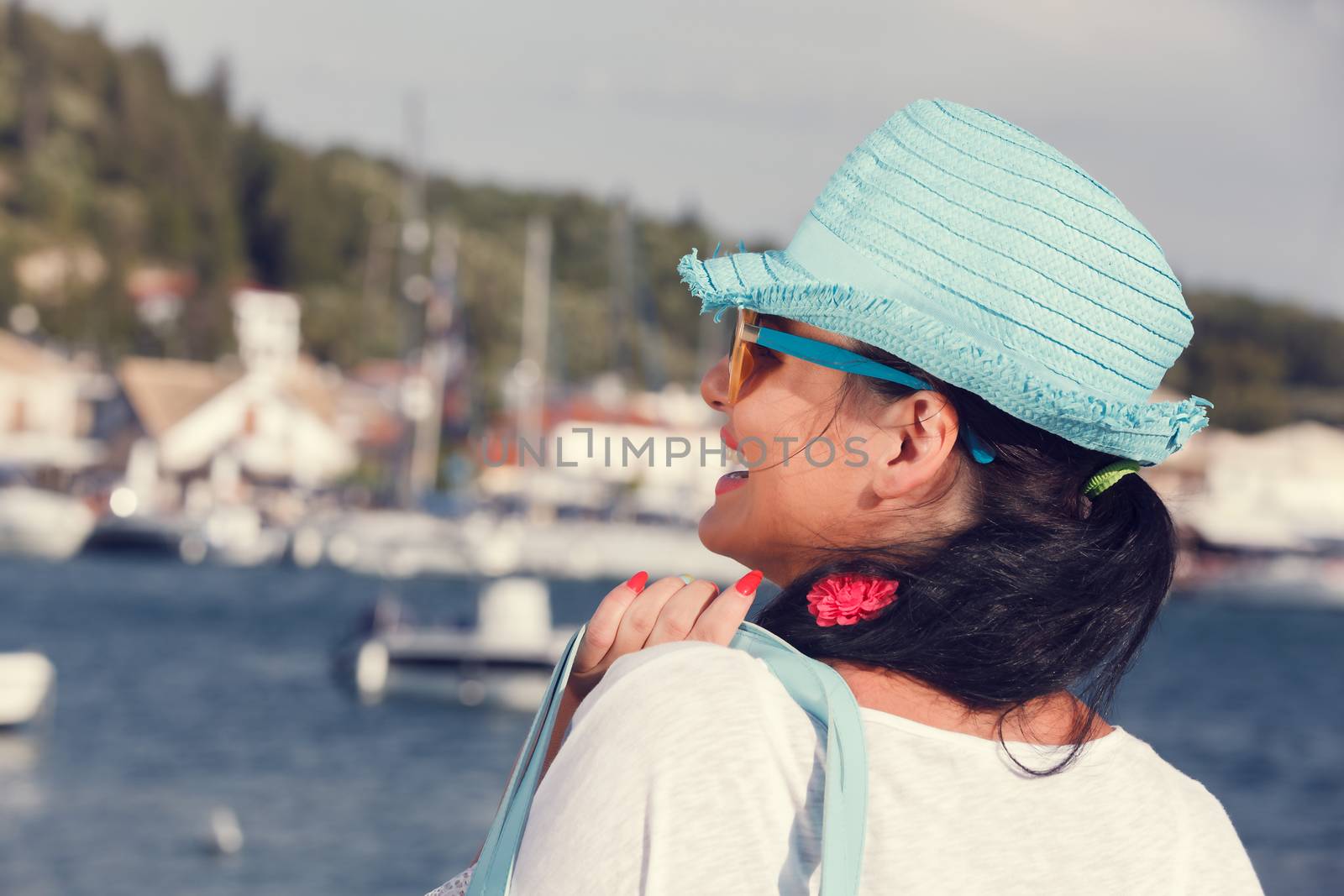 Side view of a woman wearing a straw hat looking at the sea, near the yacht marine