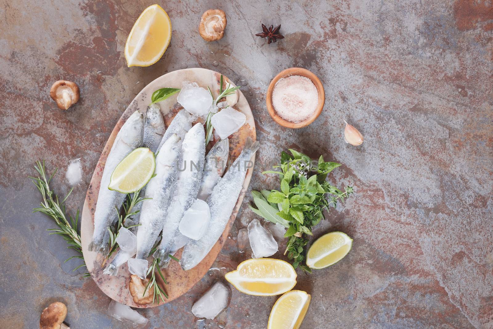 Frozen sardines. High angle view of frozen fish decorated with lemon and herbs on plate.