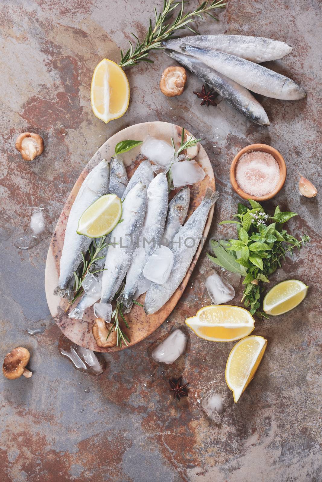 High angle view of frozen fish decorated with lemon and herbs on plate.