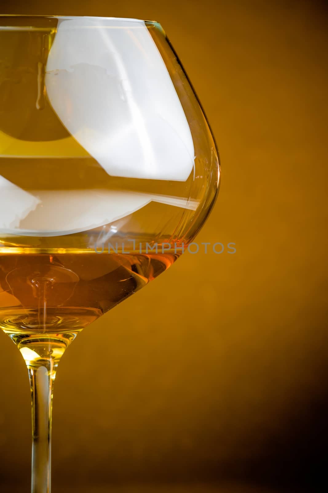 white wine into a glass with space for text, warm atmosphere by donfiore