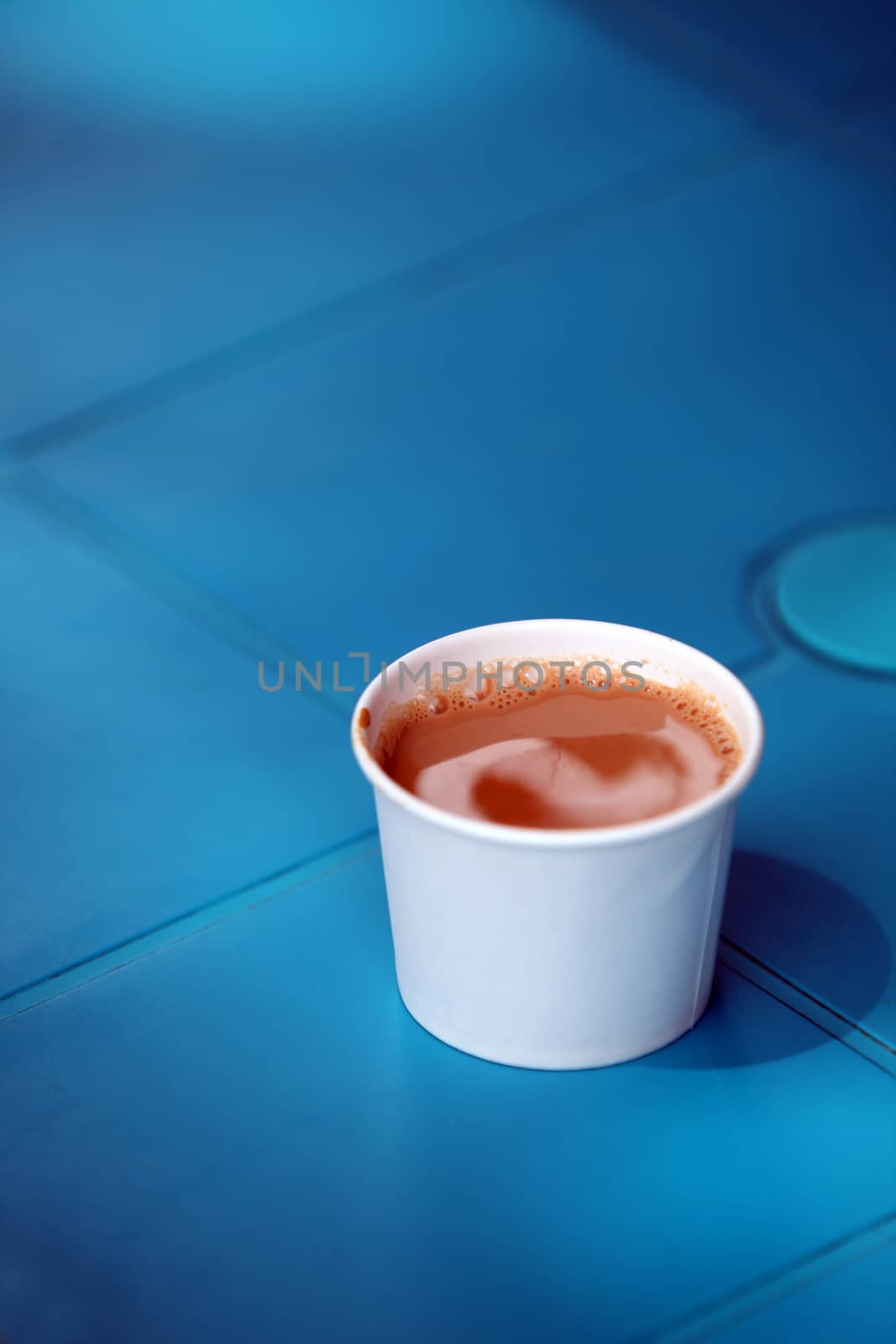 A cup of refreshing tea, kept on a bright blue colored table.