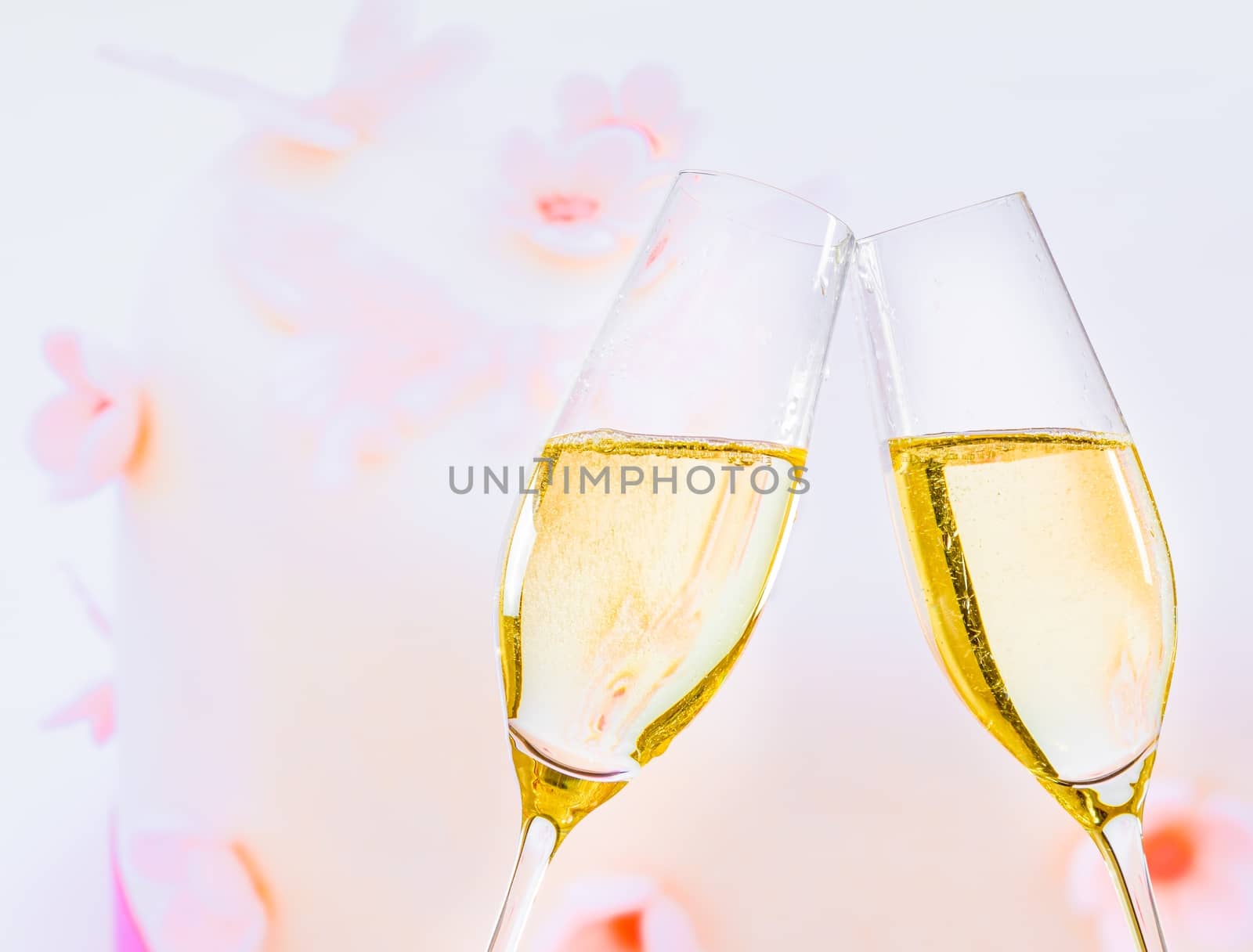 champagne flutes with golden bubbles make cheers on wedding cake background