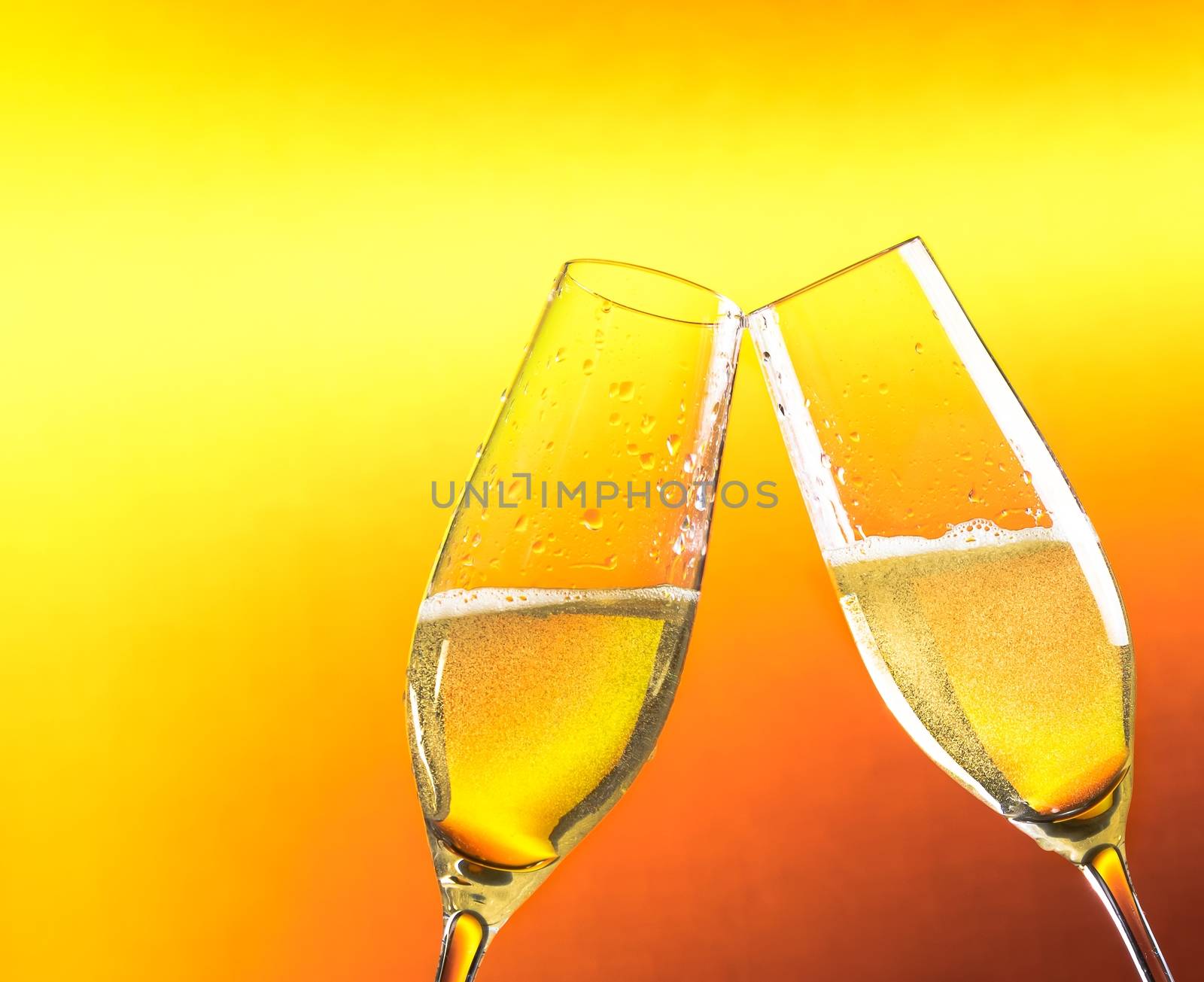 two flutes of champagne with golden bubbles and space for text against golden background