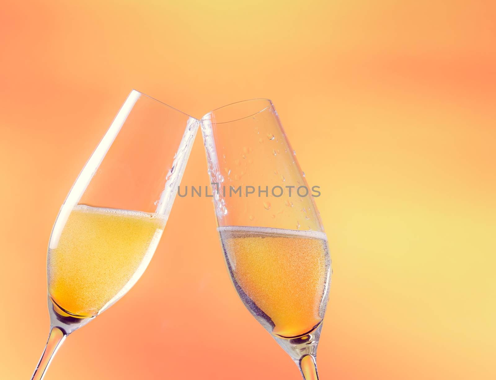 two flutes of champagne with golden bubbles and space for text on golden background