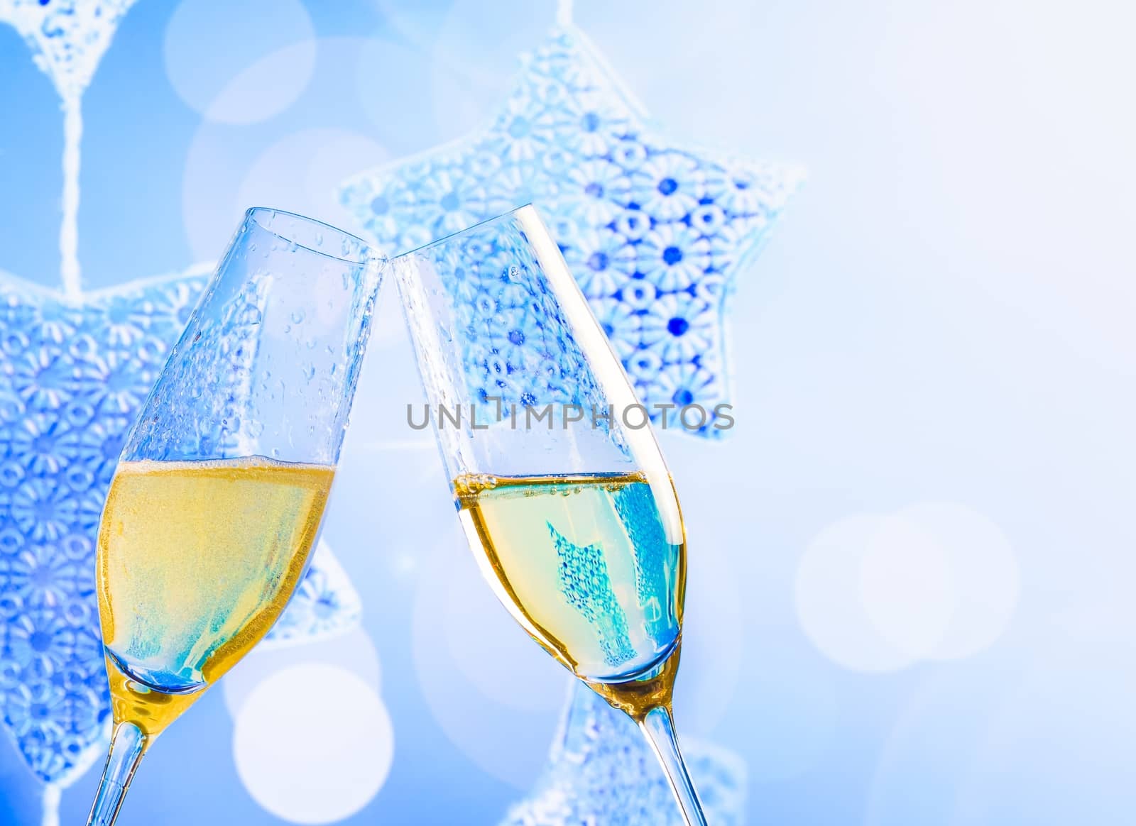 champagne flutes with golden bubbles on blue christmas lights decoration background by donfiore