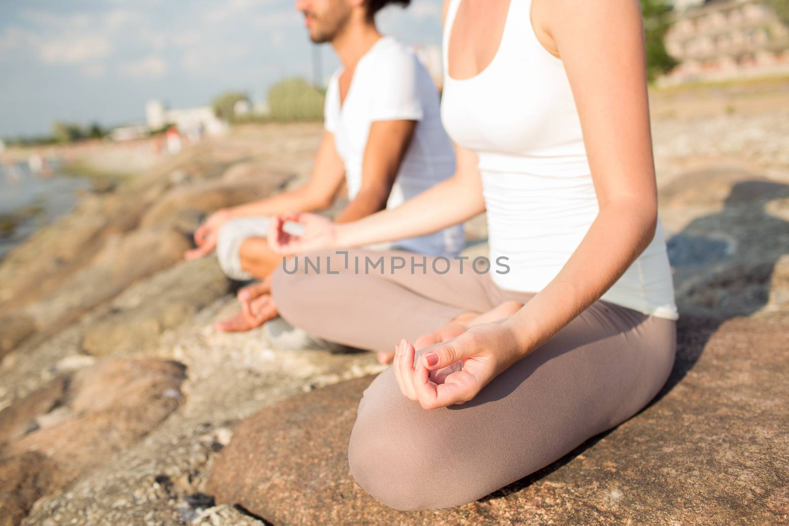 fitness, sport, people and lifestyle concept - close up of couple making yoga exercises sitting on pier outdoors