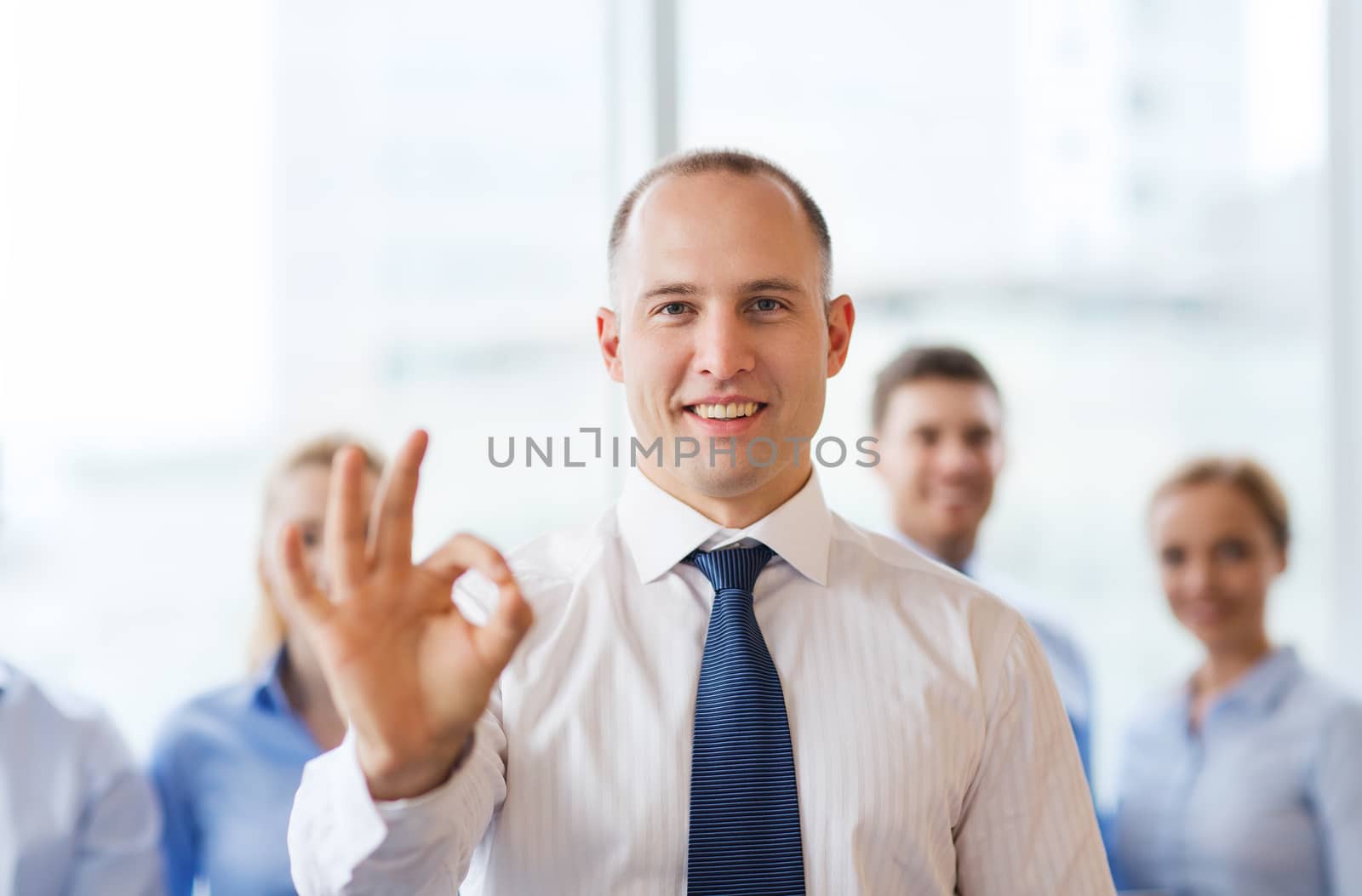 business, people, gesture and teamwork concept - smiling businessman showing ok sign with group of businesspeople in office