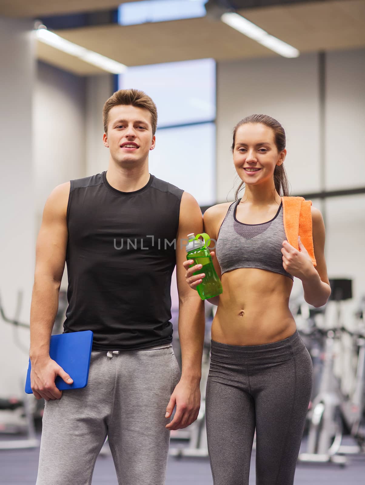 happy couple in gym with water and tablet pc by dolgachov