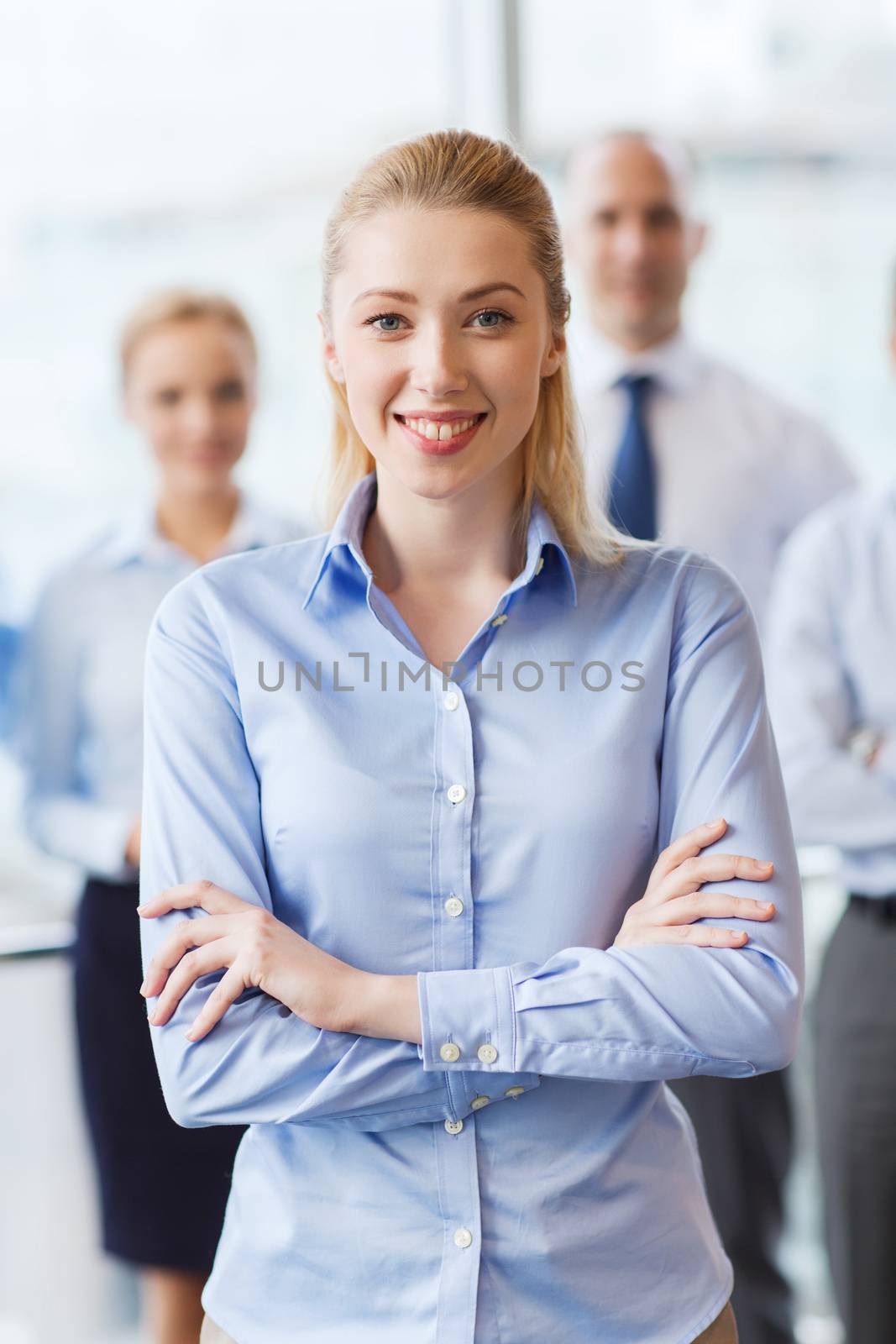 smiling businesswoman with colleagues in office by dolgachov