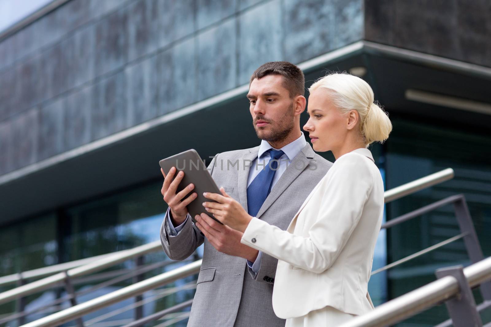 business, partnership, technology and people concept - businessman and businesswoman working with tablet pc computer on city street