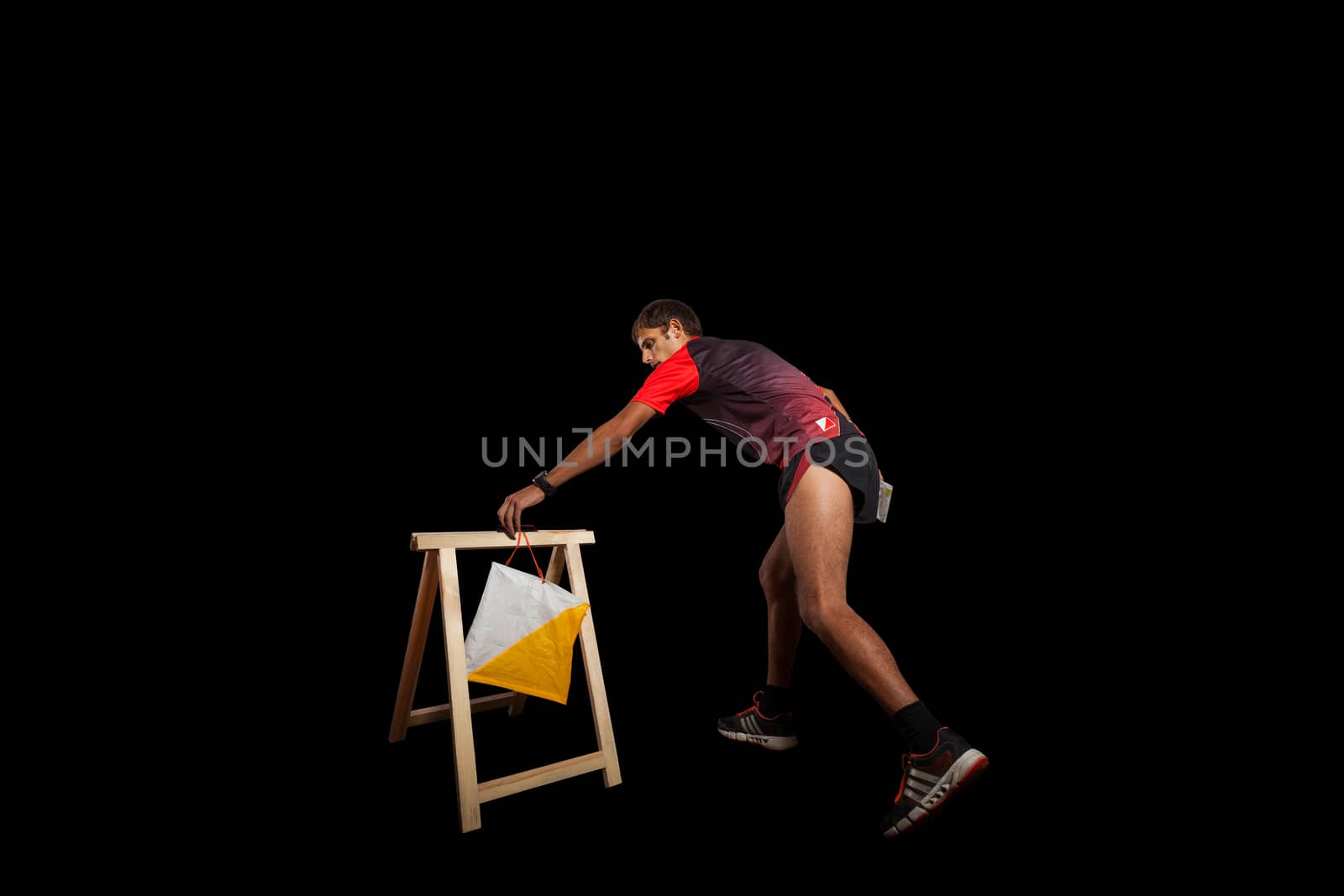 Man punching at control point, taking part in orienteering competitions. Isolated on black. File contains clipping path