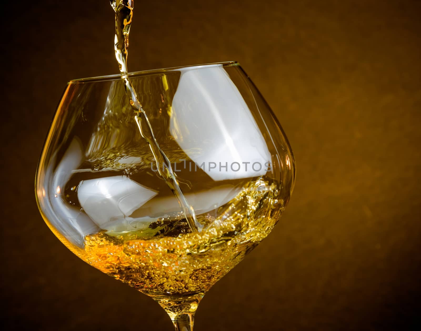 pouring white wine into a glass on golden background with space for text, warm atmosphere