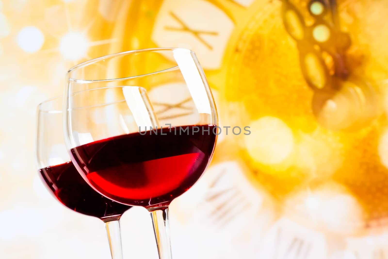 two red wine glasses against golden clock background by donfiore