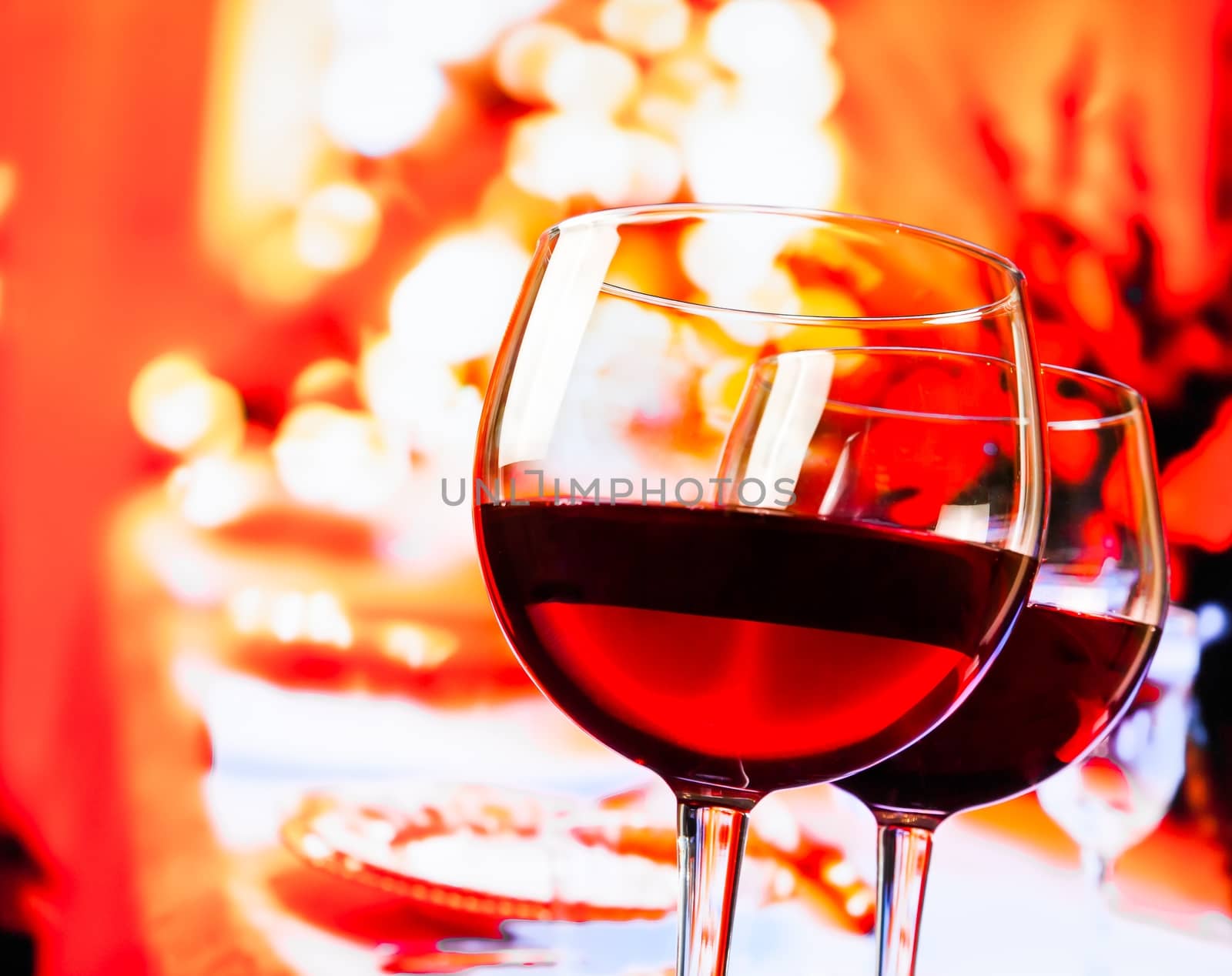 two red wine glasses against unfocused restaurant table background by donfiore