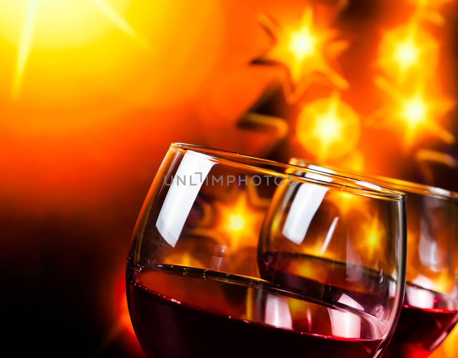 two red wine glasses against golden lights tree background, christmas atmosphere