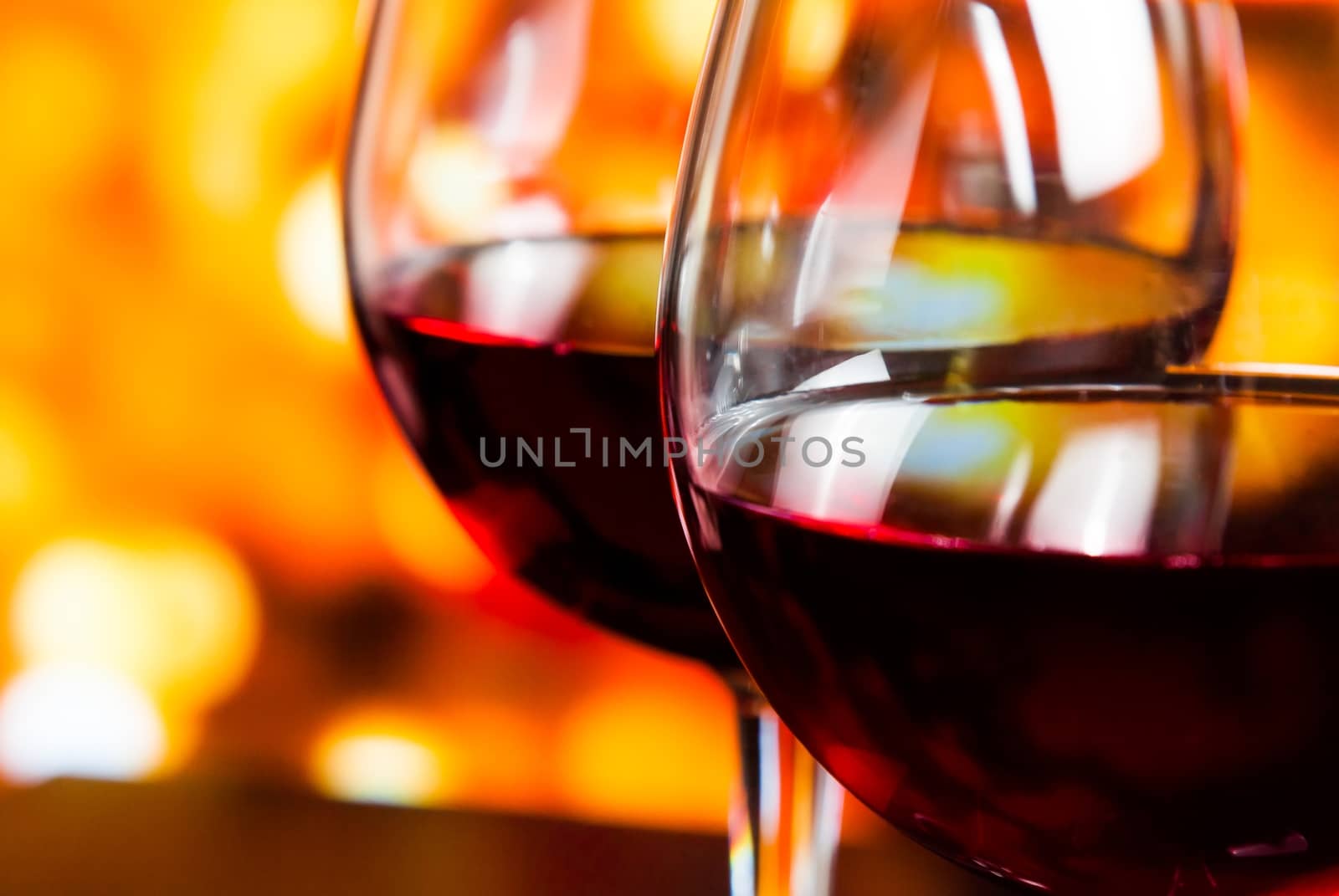 detail of two red wine glasses against colorful unfocused lights background, festive and fun concept