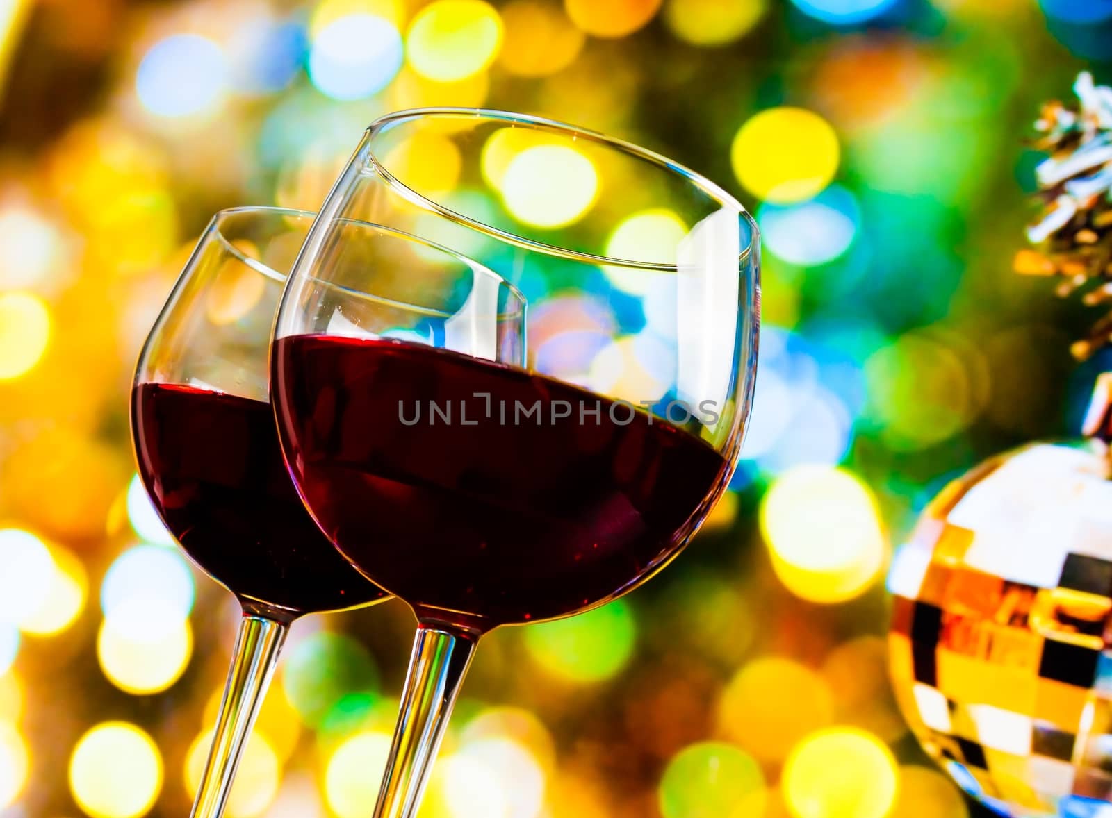 two red wine glasses against colorful bokeh lights and sparkling disco ball background by donfiore