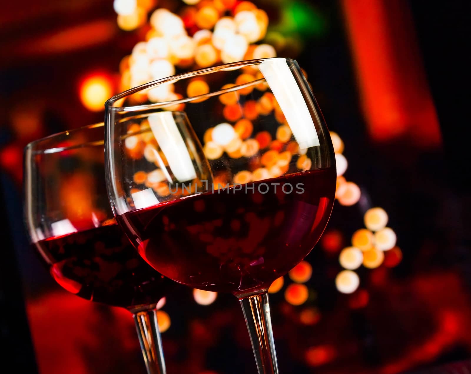 two red wine glass against christmas lights decoration background, christmas atmosphere