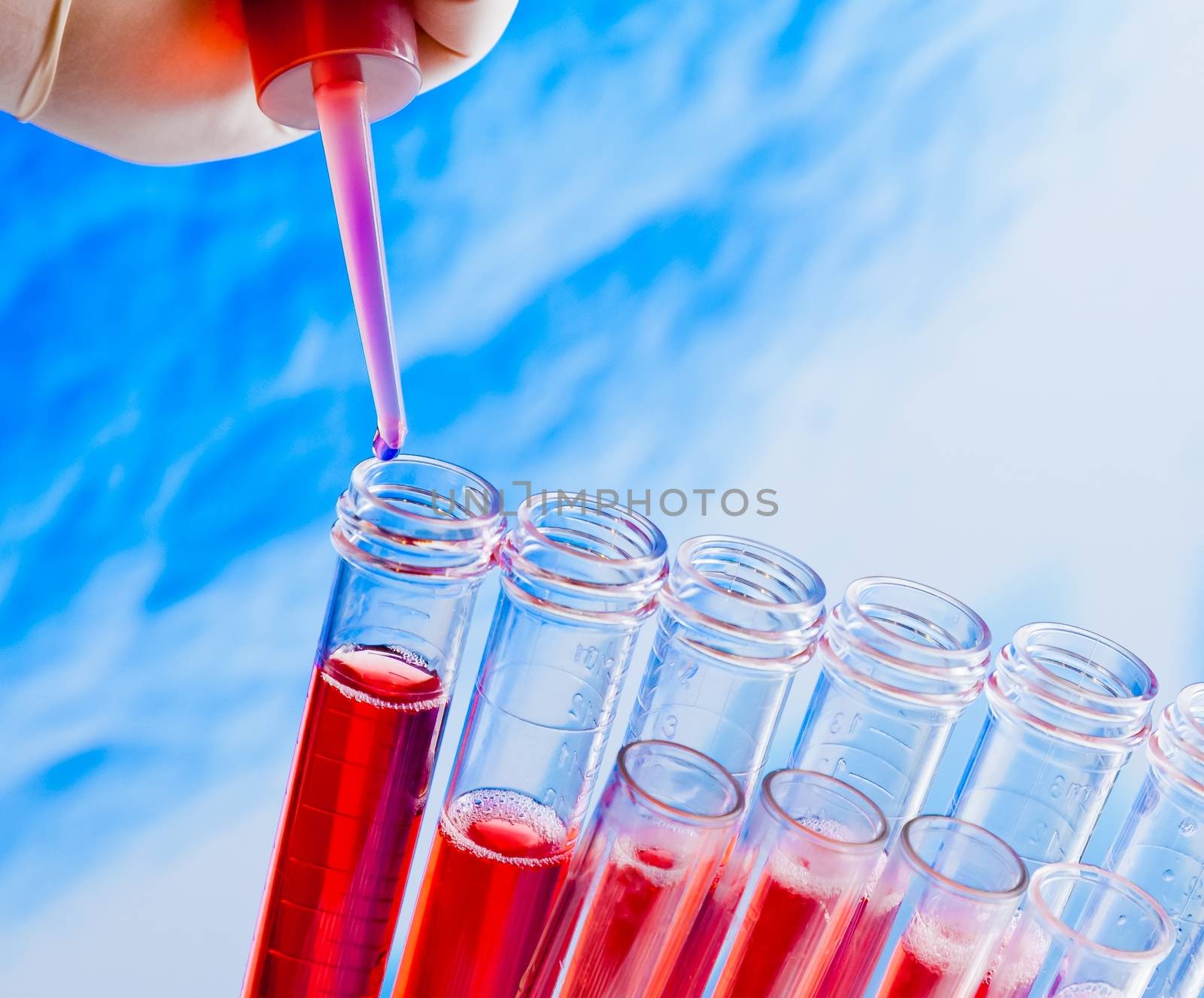 closeup of test tubes with pipette on red liquid on blue blur abstract background