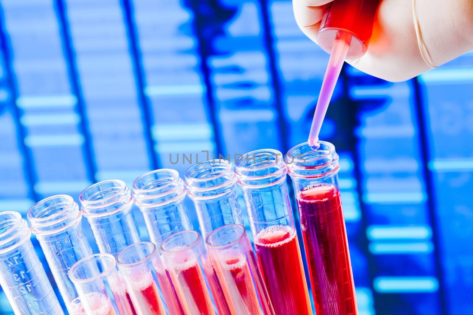 closeup of test tubes with pipette on red liquid on blue blur abstract dna sequence background