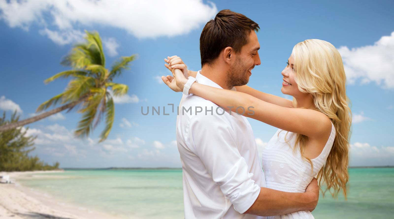summer holidays, people, love, travel and dating concept - happy couple hugging over tropical beach background