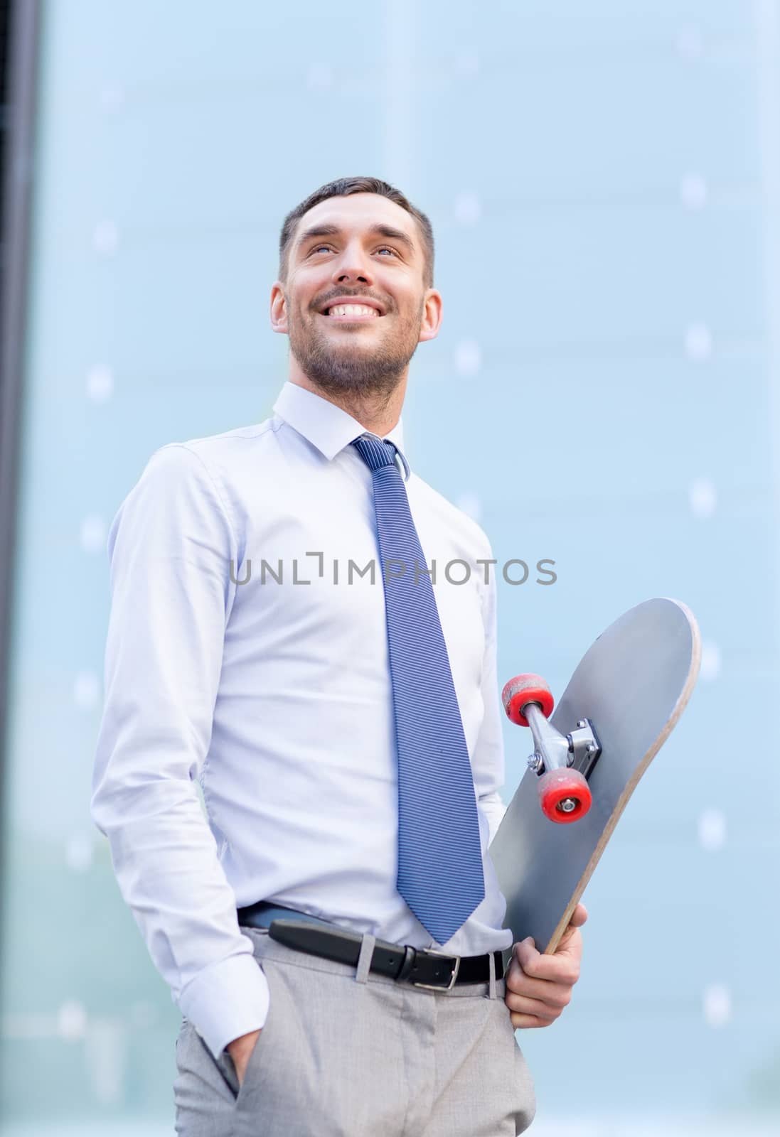 young smiling businessman with skateboard outdoors by dolgachov