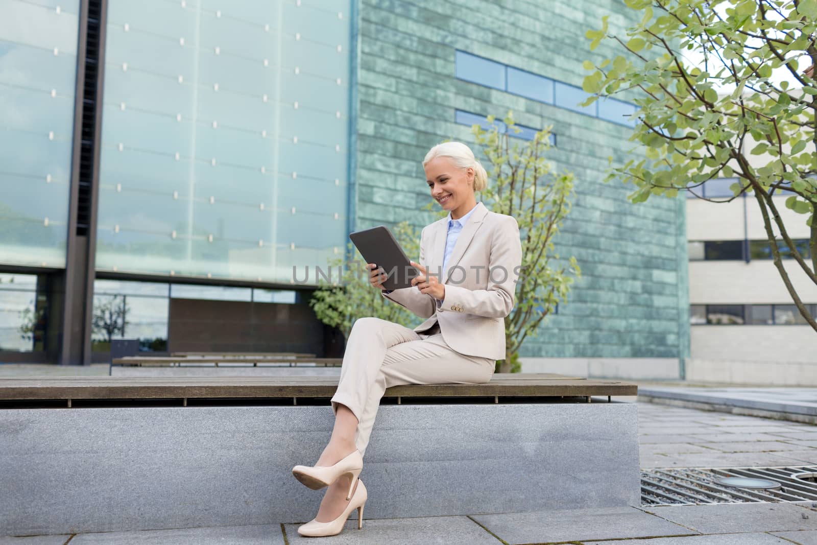 business, education, technology and people concept - smiling businesswoman working with tablet pc computer on city street