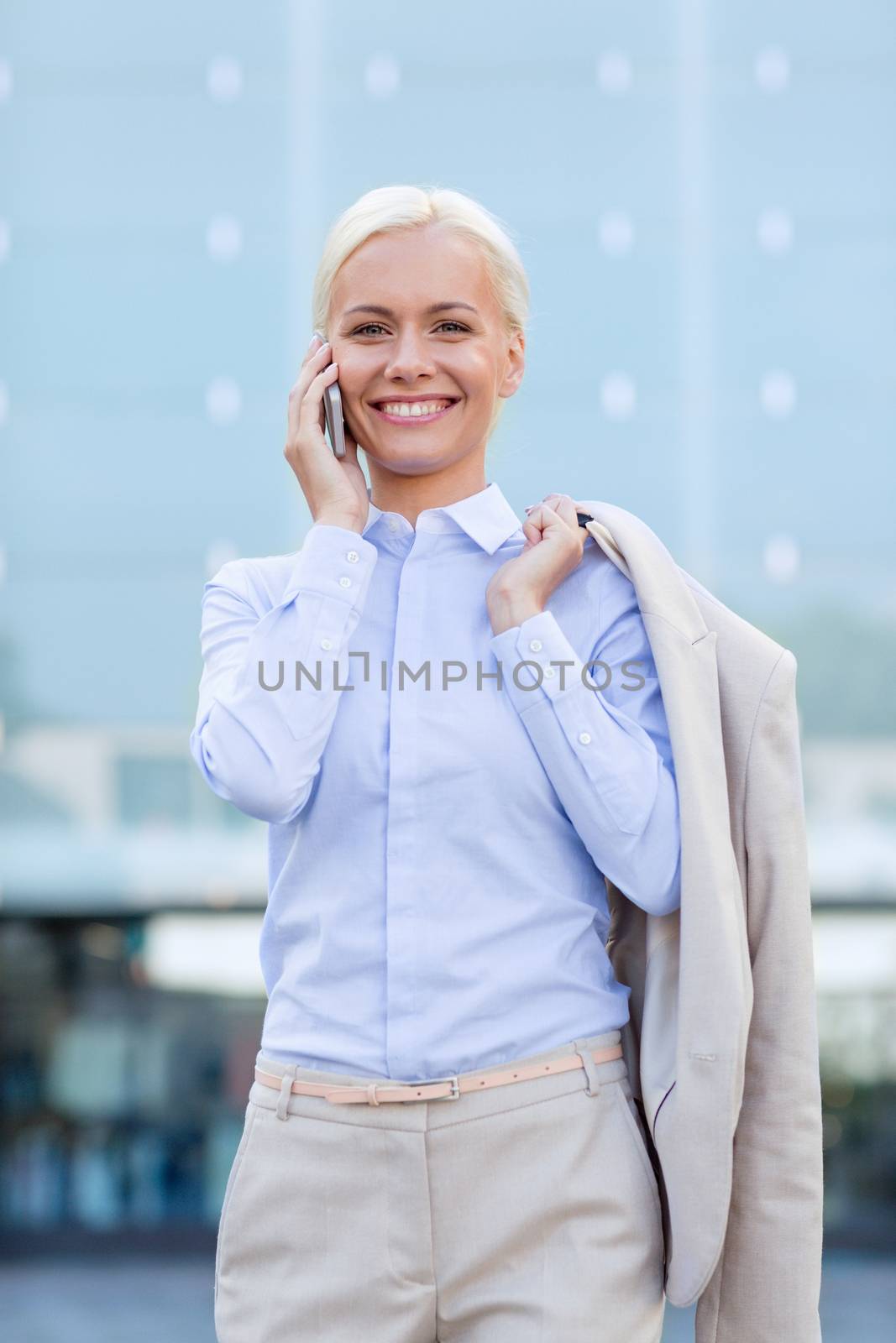 smiling businesswoman with smartphone outdoors by dolgachov