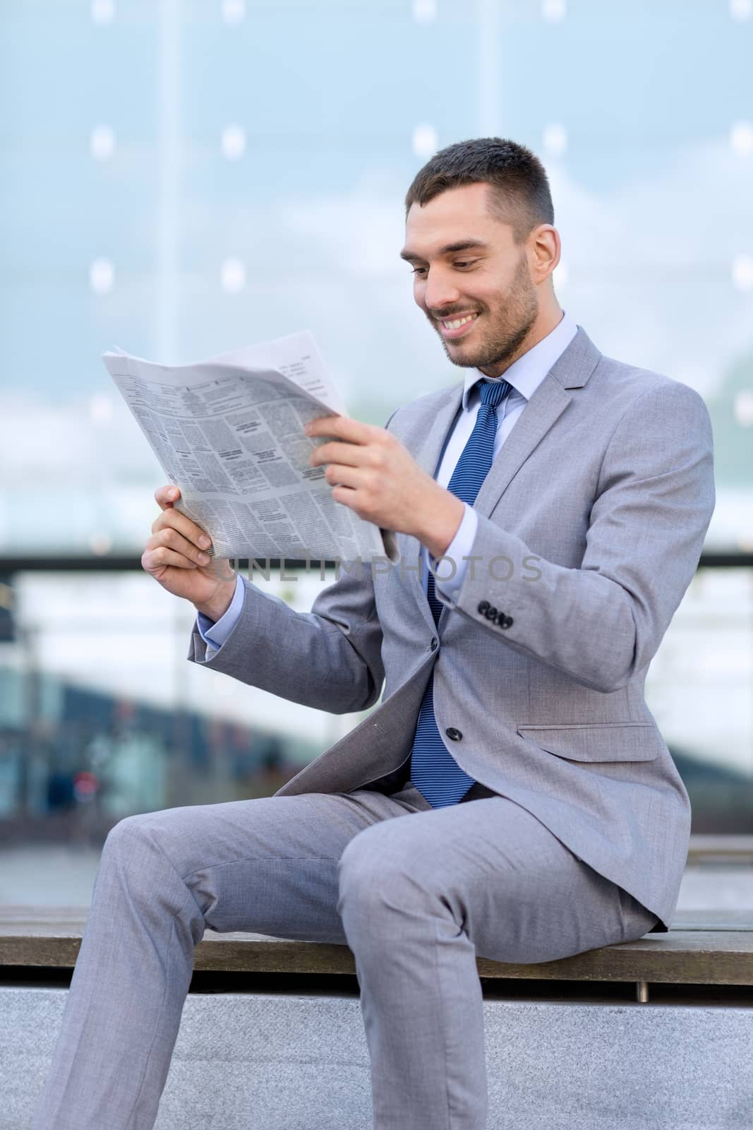 young smiling businessman newspaper outdoors by dolgachov