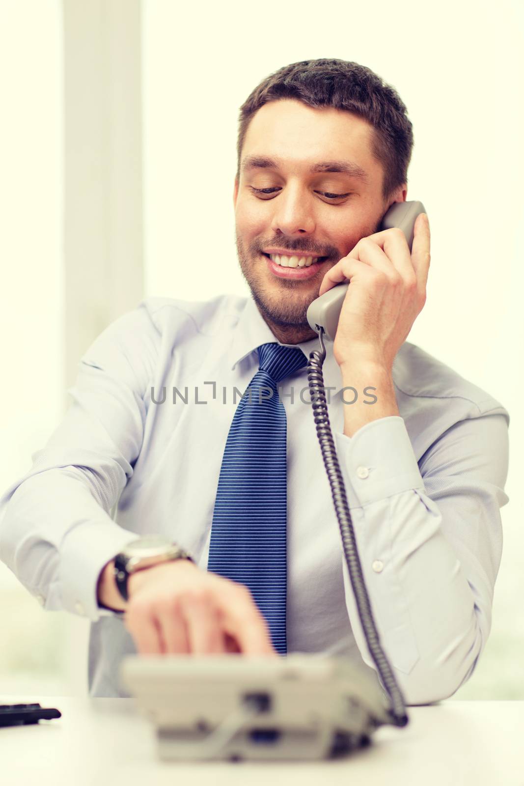 smiling businessman with telephone dialing number by dolgachov